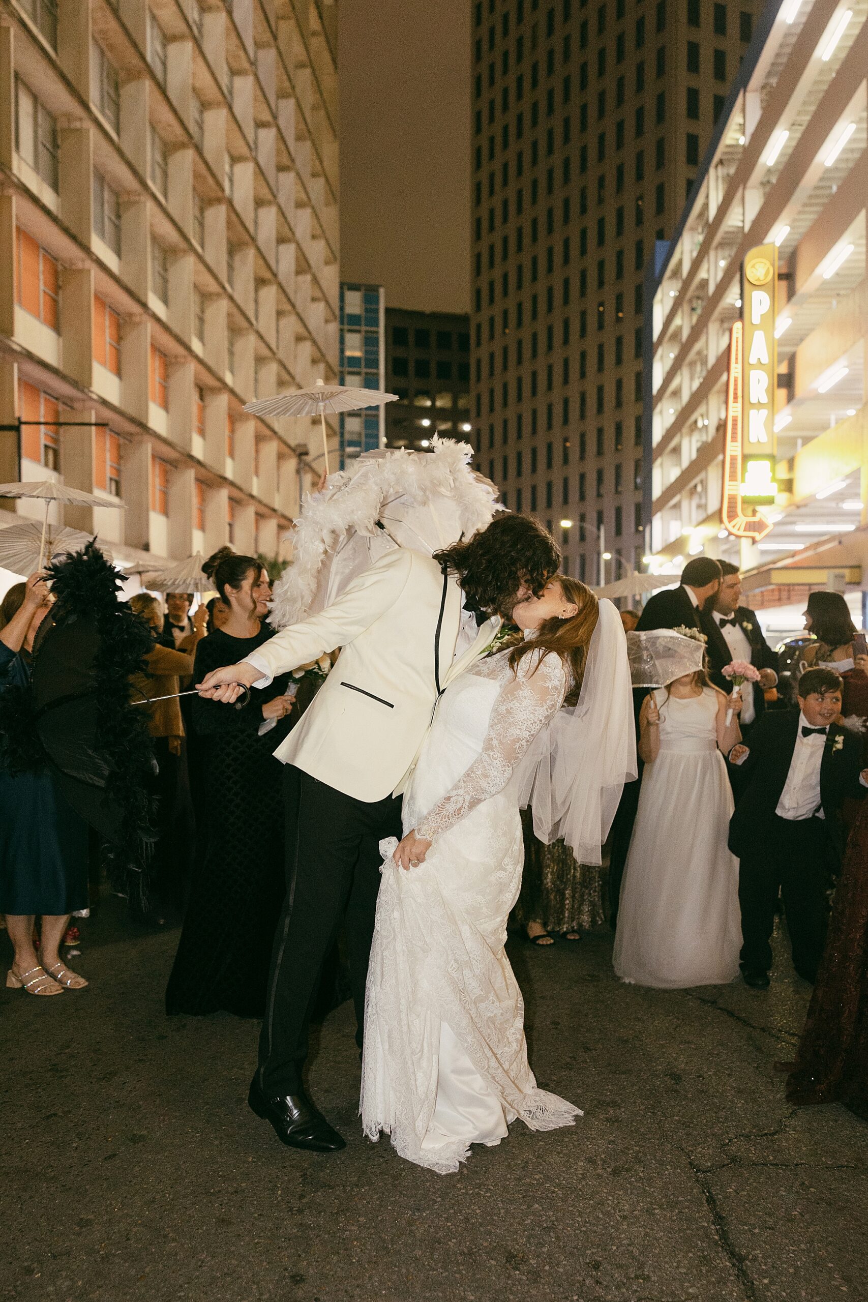 bride and groom kissing in the street with a crowd cheering them on
