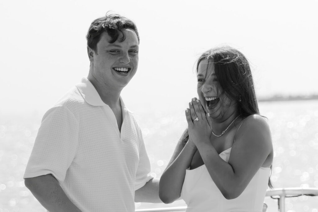 A couple sharing a sweet moment during a surprise sailboat proposal at sea.
