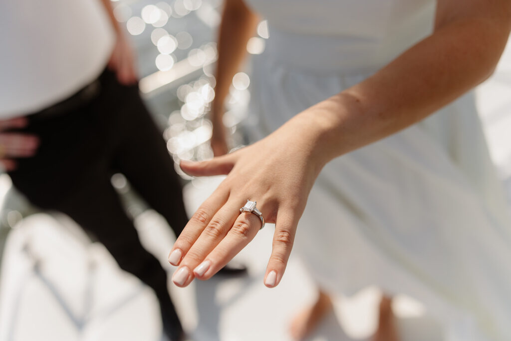 A couple sharing a sweet moment during a surprise sailboat proposal at sea.
