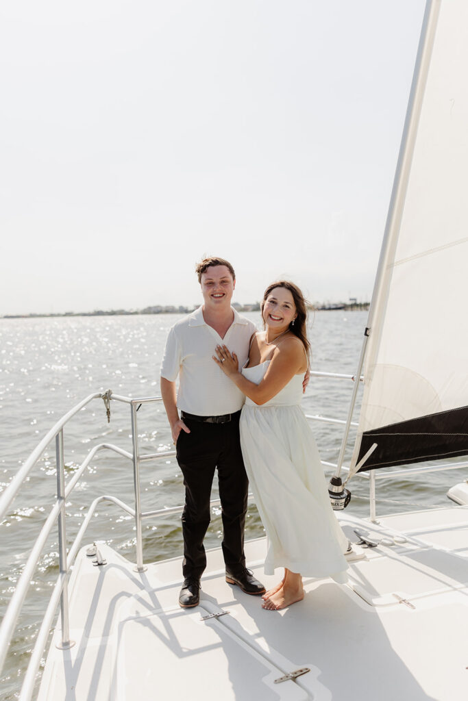 A romantic sailboat proposal captured with the couple posing together on deck.
