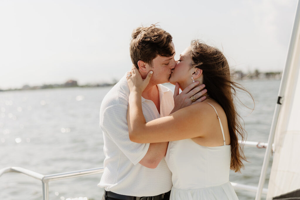 A couple sharing a sweet moment during a surprise sailboat proposal at sea.
