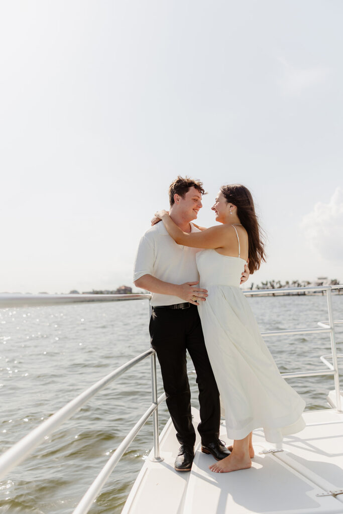 A couple sharing a sweet moment during a surprise sailboat proposal at sea.
