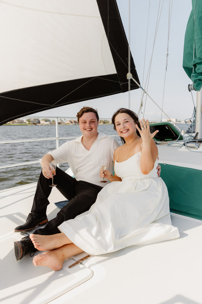 A romantic sailboat proposal captured with the couple posing together on deck.
