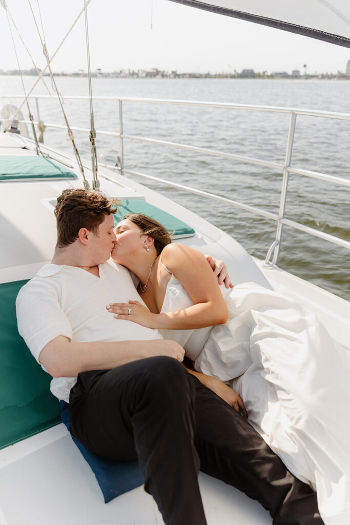 A joyful couple embracing after a surprise proposal on a sailboat in open water.
