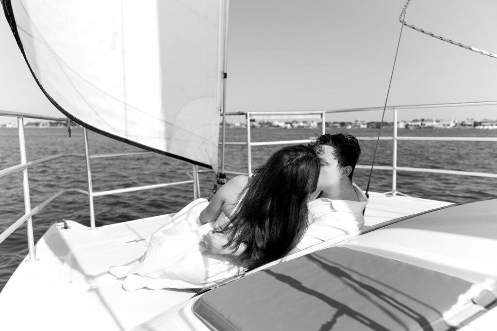 A couple sharing a sweet moment during a surprise sailboat proposal at sea.
