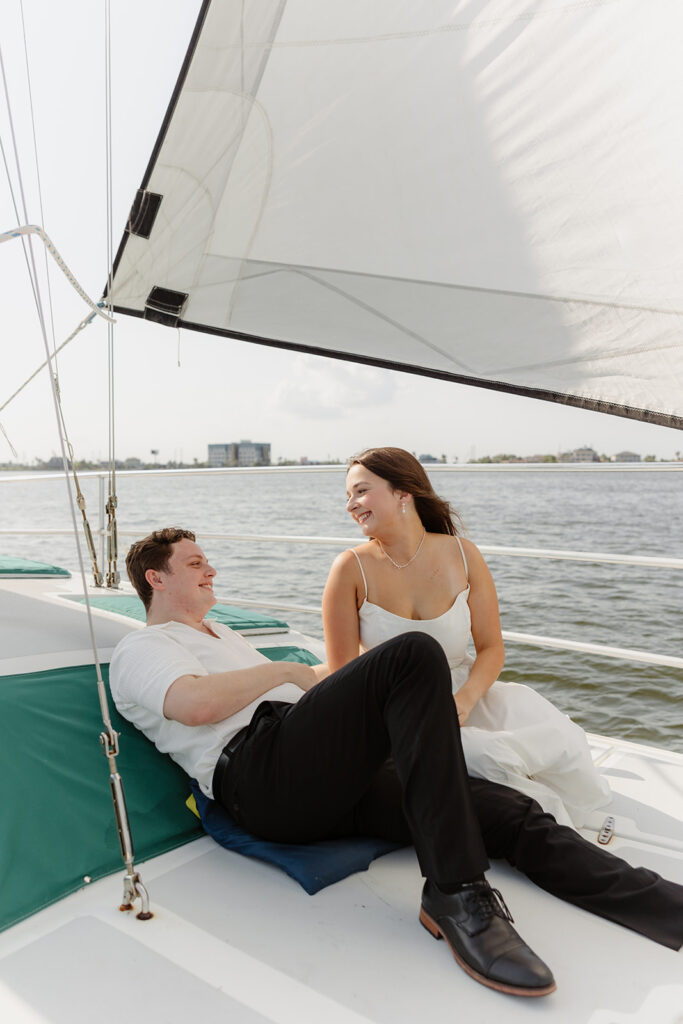 A joyful couple embracing after a surprise proposal on a sailboat in open water.
