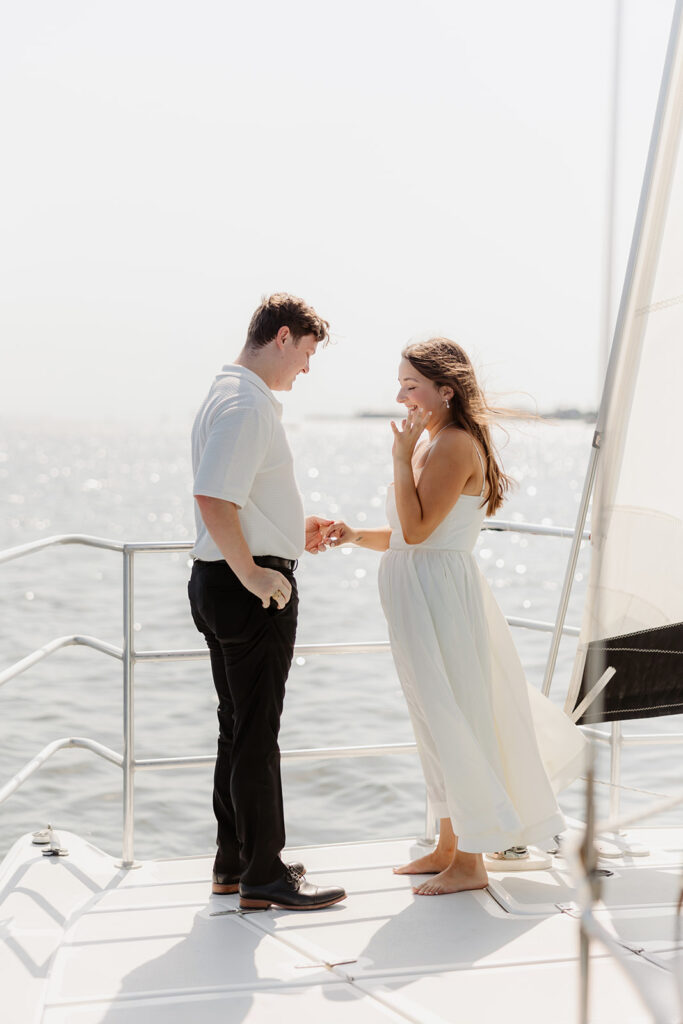 A couple sharing a sweet moment during a surprise sailboat proposal at sea.
