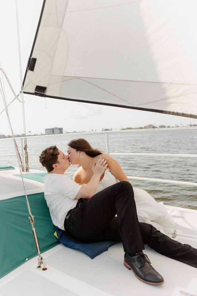 A joyful couple embracing after a surprise proposal on a sailboat in open water.
