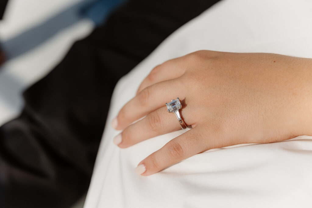 A joyful couple embracing after a surprise proposal on a sailboat in open water.
