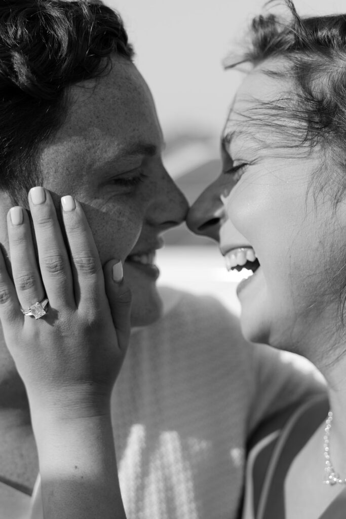 A couple sharing a sweet moment during a surprise sailboat proposal at sea.
