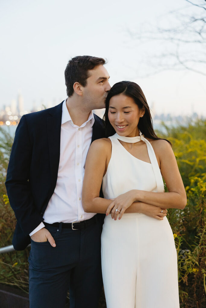 A couple sharing romantic moments during their early morning engagement session at Domino Park, Brooklyn, with the soft blue hour light setting the scene.
