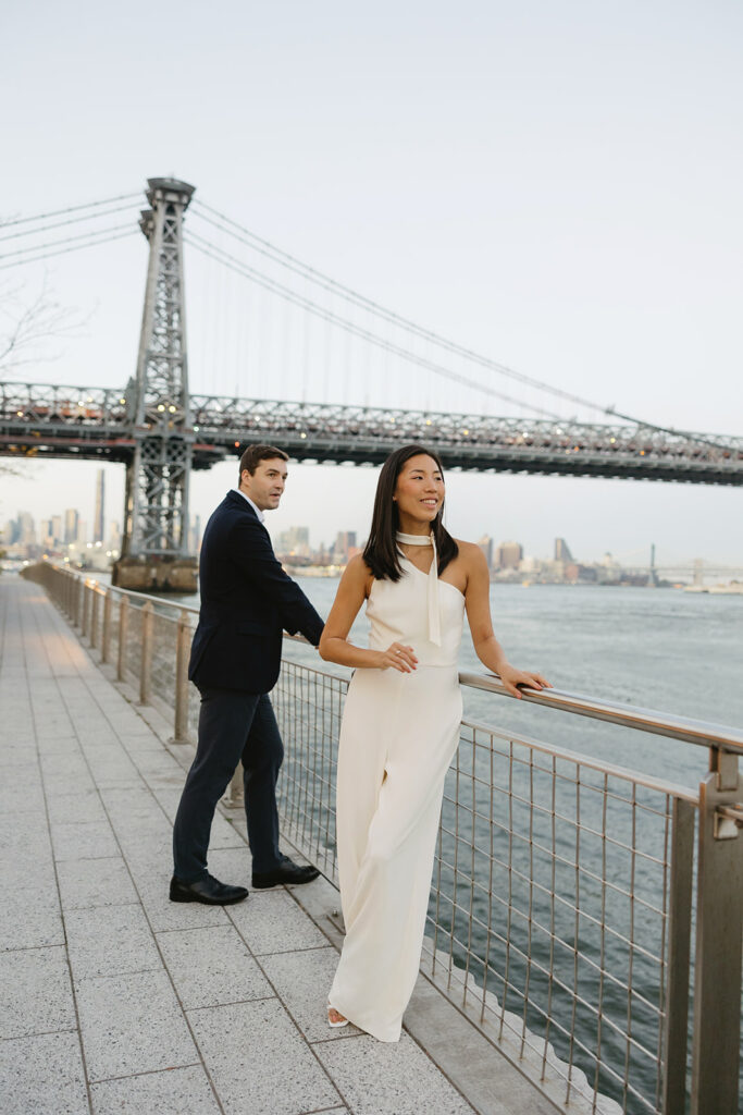 An engaged couple standing together in Domino Park, Brooklyn, as the sun begins to rise, capturing the peaceful vibe of the blue hour.
