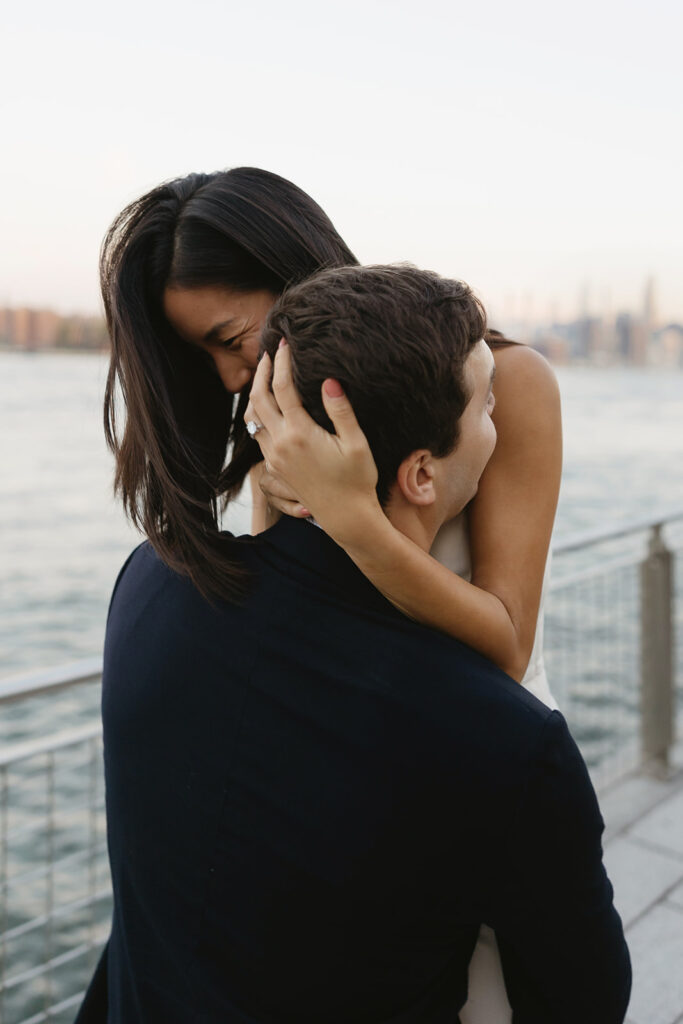 A couple sharing romantic moments during their early morning engagement session at Domino Park, Brooklyn, with the soft blue hour light setting the scene.
