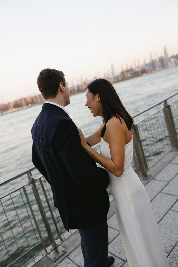 An engaged couple standing together in Domino Park, Brooklyn, as the sun begins to rise, capturing the peaceful vibe of the blue hour.
