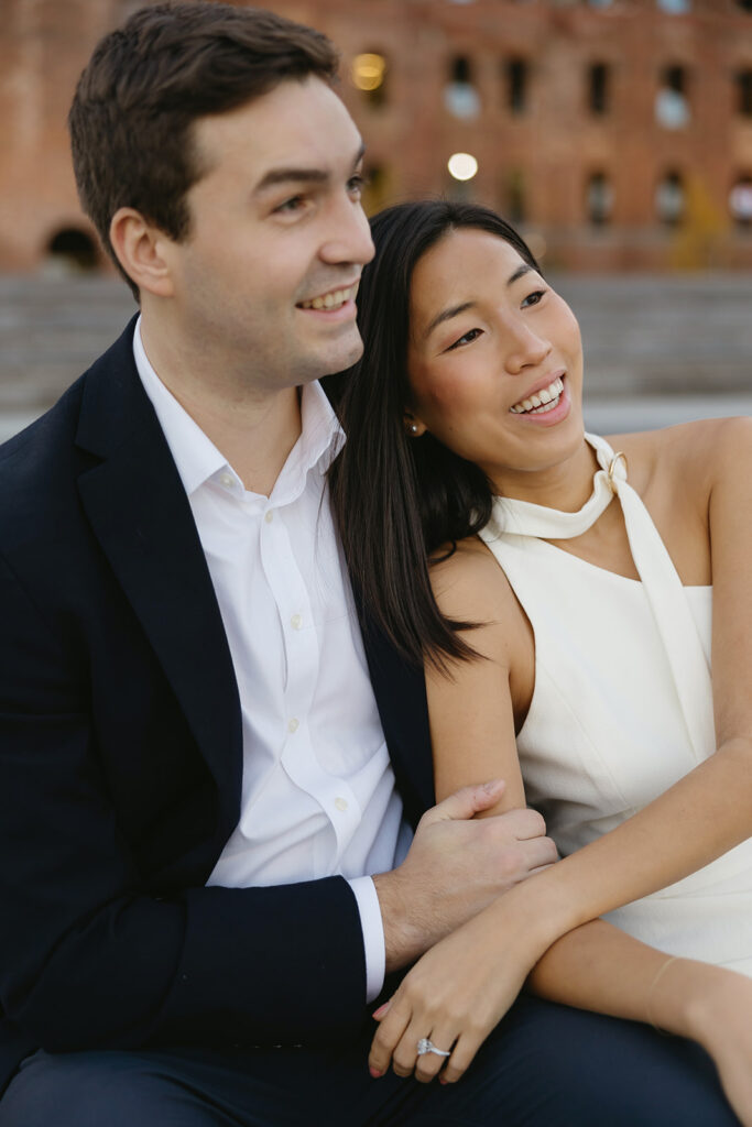 A couple sharing romantic moments during their early morning engagement session at Domino Park, Brooklyn, with the soft blue hour light setting the scene.