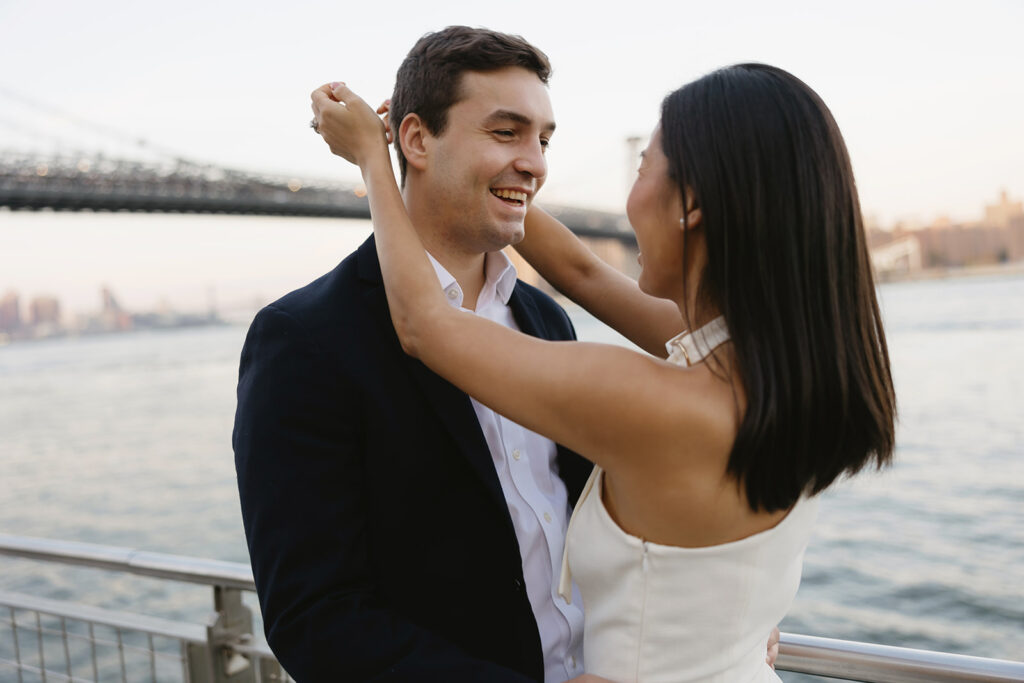 A pair embracing at Domino Park in Brooklyn during their sunrise engagement shoot, surrounded by a calm, pre-dawn atmosphere.