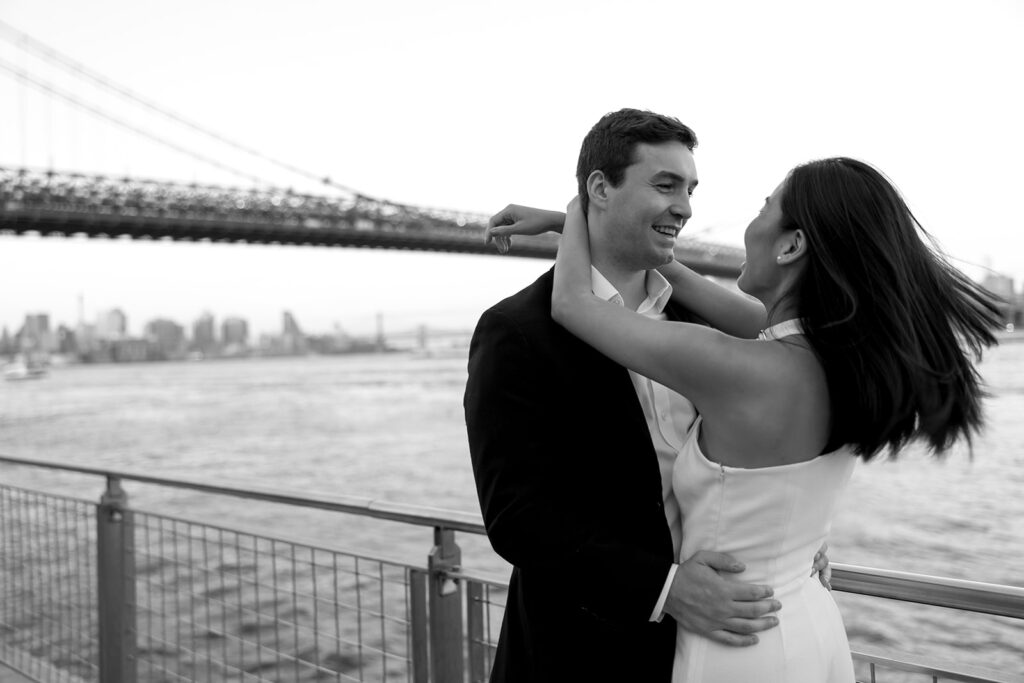 A pair embracing at Domino Park in Brooklyn during their sunrise engagement shoot, surrounded by a calm, pre-dawn atmosphere.
