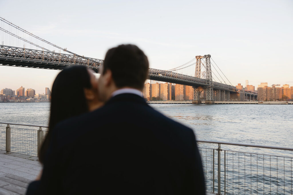 A pair embracing at Domino Park in Brooklyn during their sunrise engagement shoot, surrounded by a calm, pre-dawn atmosphere.
