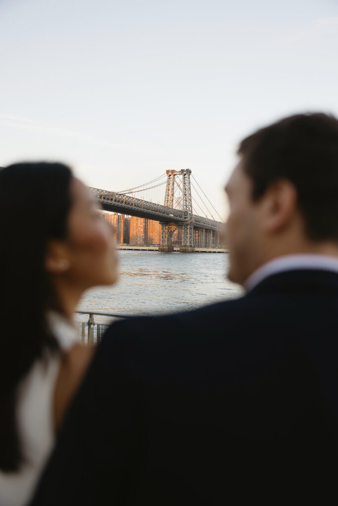 A pair embracing at Domino Park in Brooklyn during their sunrise engagement shoot, surrounded by a calm, pre-dawn atmosphere.
