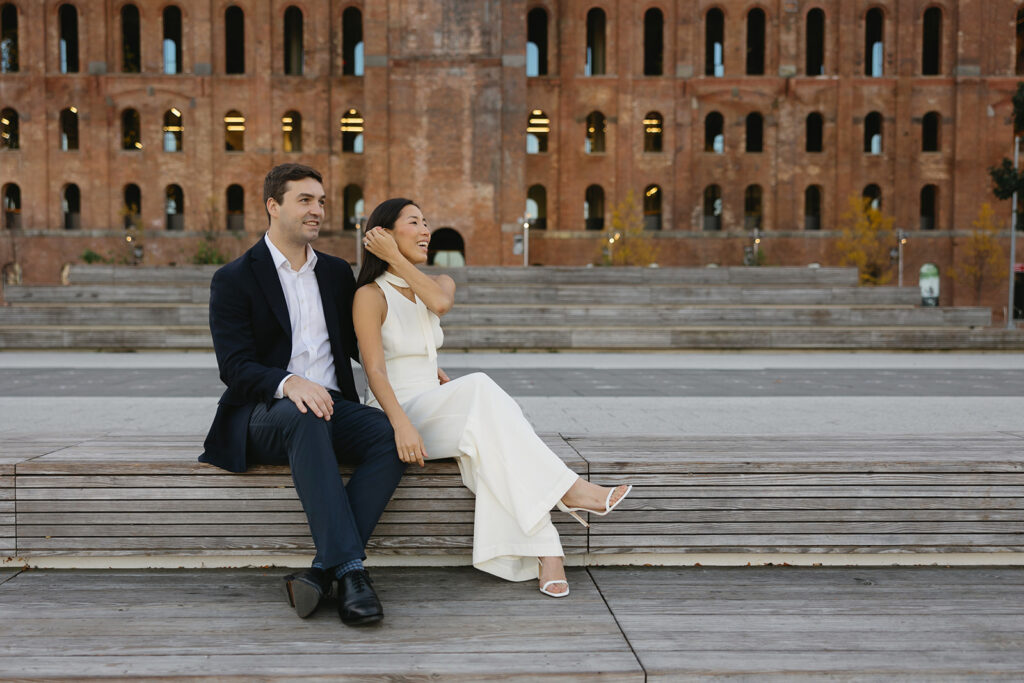 A pair embracing at Domino Park in Brooklyn during their sunrise engagement shoot, surrounded by a calm, pre-dawn atmosphere.
