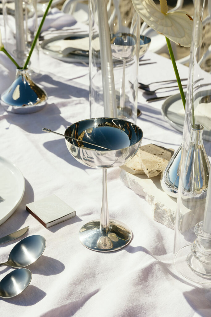 Modern coastal wedding table setup with silver flatware and linen decor
