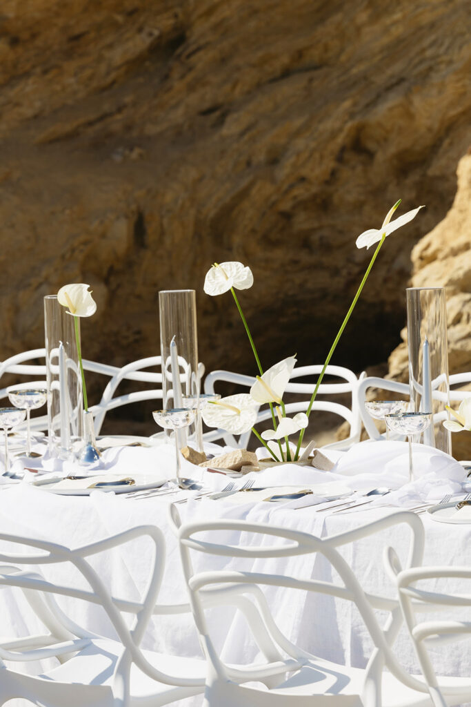 Modern coastal wedding table setup with silver flatware and linen decor
