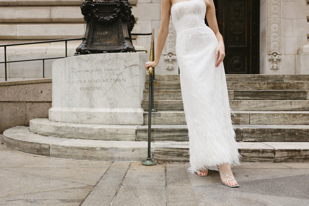 Bride standing on the steps of the New York Public Library in a wedding dress
